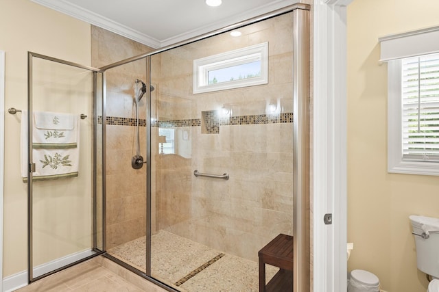 bathroom with toilet, a shower stall, ornamental molding, and baseboards