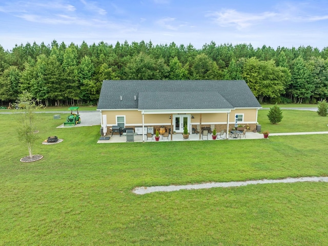 rear view of property featuring french doors, a patio area, a lawn, and a fire pit