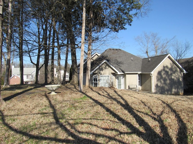 exterior space featuring a front yard and roof with shingles