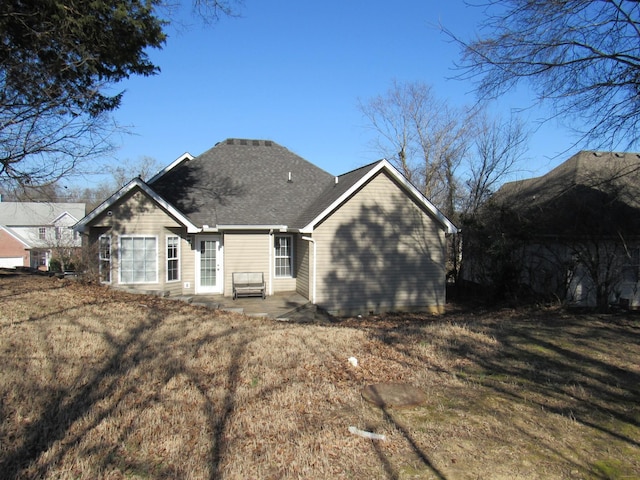 rear view of property with roof with shingles and a lawn