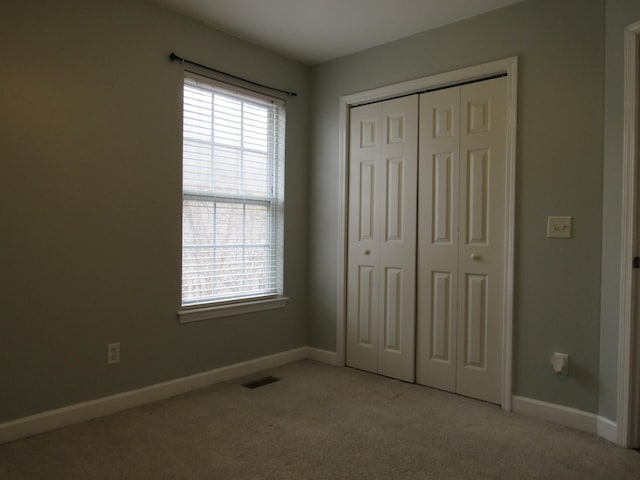 unfurnished bedroom with light colored carpet, a closet, visible vents, and baseboards