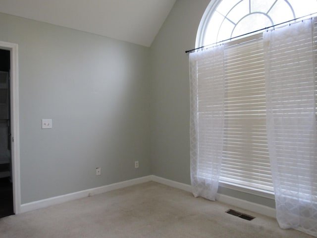 unfurnished room with lofted ceiling, carpet, visible vents, and baseboards