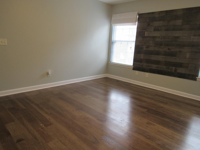 unfurnished room featuring baseboards and dark wood-style flooring