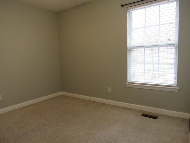 empty room featuring carpet, visible vents, and baseboards