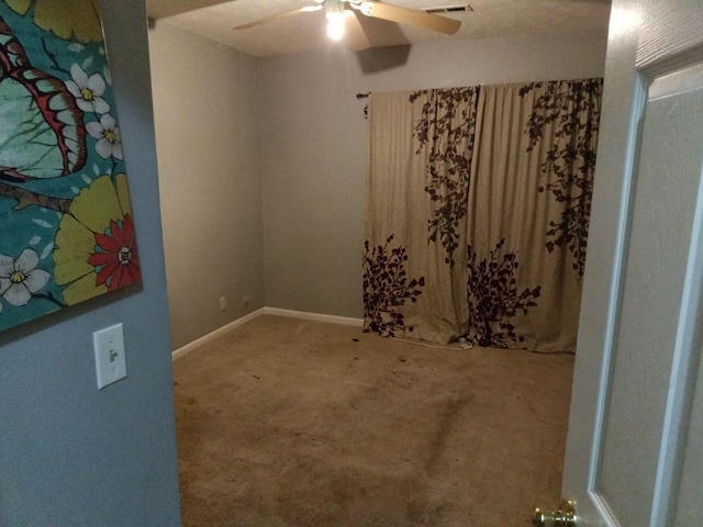 carpeted empty room with ceiling fan, visible vents, and baseboards