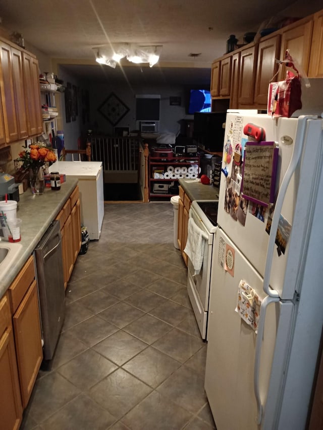 kitchen with brown cabinets, light countertops, dark tile patterned flooring, white appliances, and a peninsula