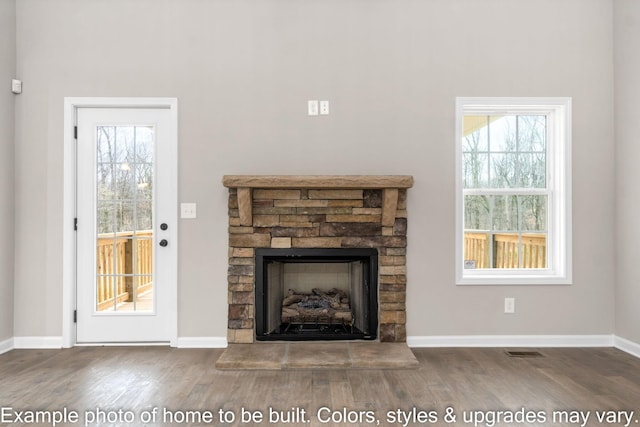 unfurnished living room featuring a fireplace with raised hearth, wood finished floors, visible vents, and baseboards