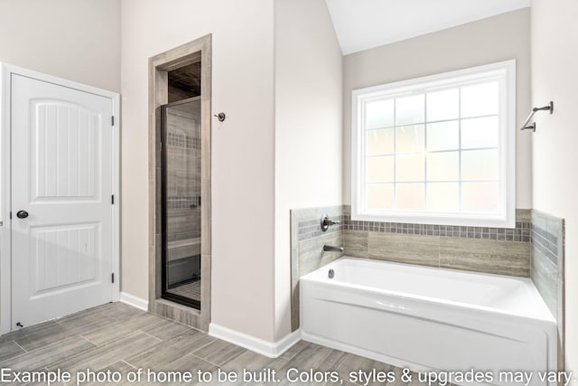 full bath with wood finish floors, a garden tub, a shower stall, and baseboards