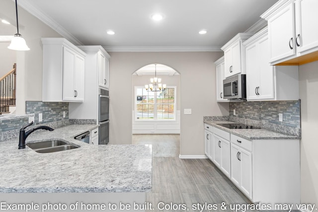 kitchen with arched walkways, a sink, white cabinets, appliances with stainless steel finishes, and light stone countertops