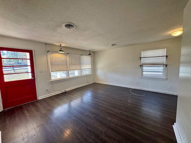 unfurnished room with baseboards, dark wood finished floors, visible vents, and a healthy amount of sunlight