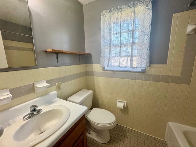 full bath featuring toilet, a wainscoted wall, tile walls, vanity, and tile patterned floors