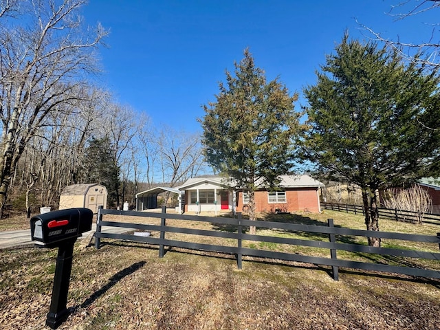 single story home with a storage shed, a fenced front yard, and an outdoor structure