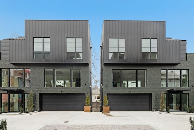 contemporary home featuring driveway, brick siding, and an attached garage