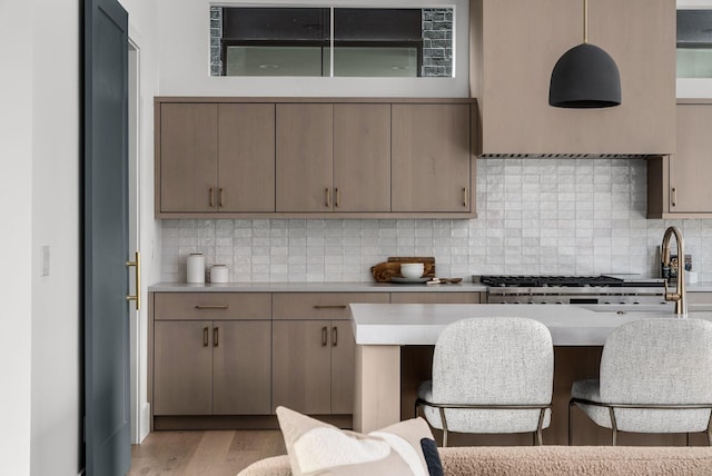 kitchen featuring light wood finished floors, tasteful backsplash, a kitchen bar, and light countertops