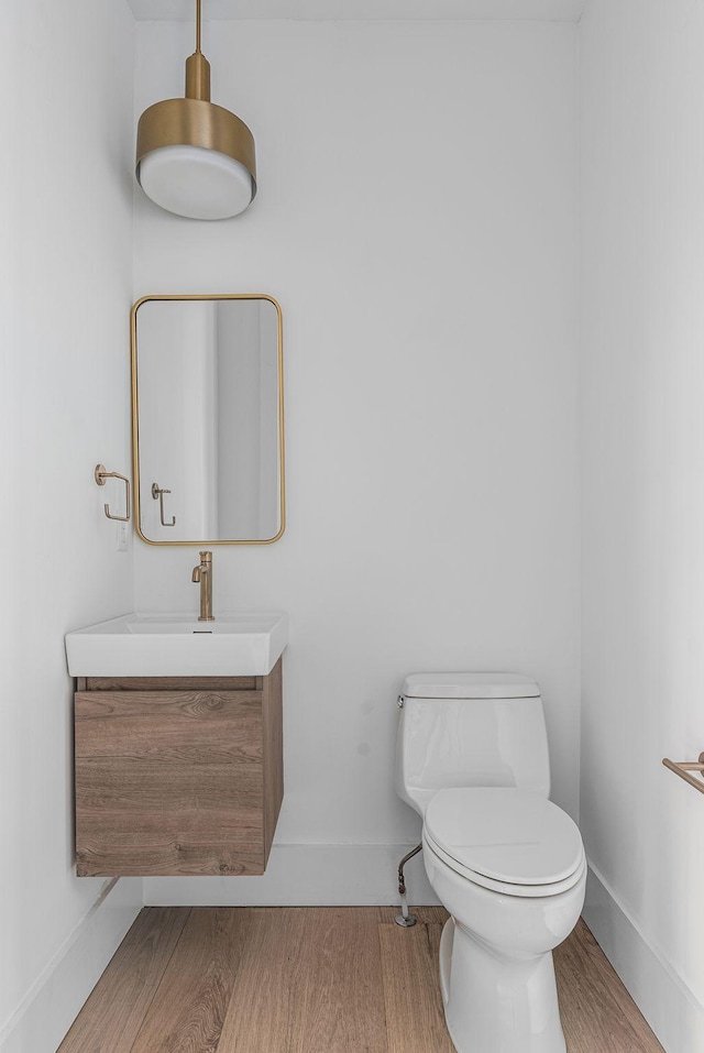 bathroom with vanity, wood finished floors, toilet, and baseboards