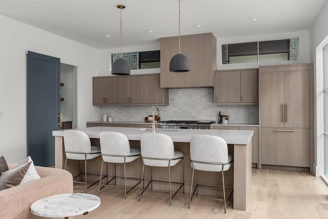 kitchen featuring light wood-style floors, a breakfast bar area, light countertops, and decorative backsplash