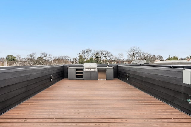 wooden deck with exterior kitchen and a grill