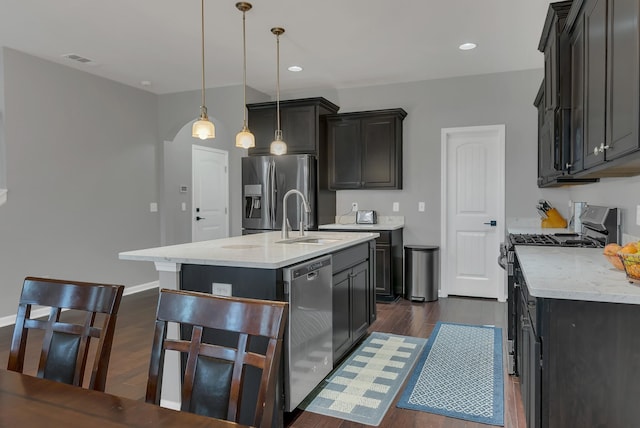 kitchen with a sink, visible vents, appliances with stainless steel finishes, an island with sink, and dark wood finished floors