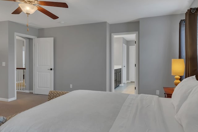 bedroom featuring light carpet, baseboards, a ceiling fan, and ensuite bathroom