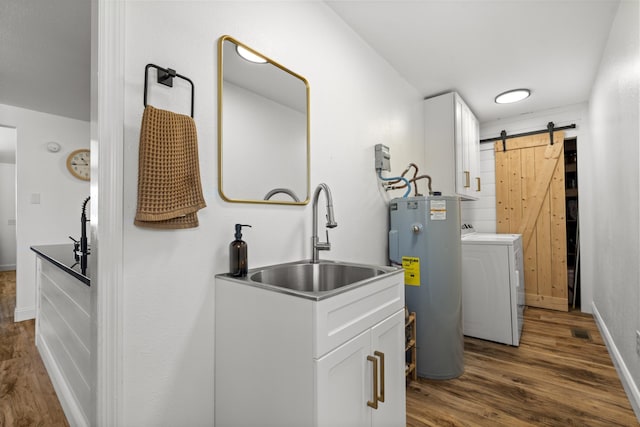 laundry area featuring a barn door, dark wood finished floors, washer / clothes dryer, electric water heater, and a sink