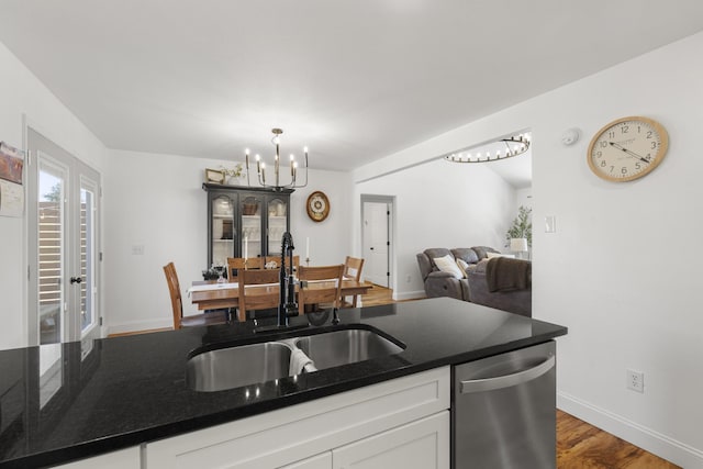 kitchen featuring a chandelier, wood finished floors, a sink, white cabinets, and dishwasher