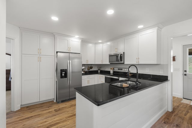 kitchen with white cabinets, light wood-style floors, stainless steel appliances, and a sink