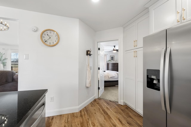 kitchen with stainless steel fridge, baseboards, white cabinets, dark stone countertops, and light wood-type flooring