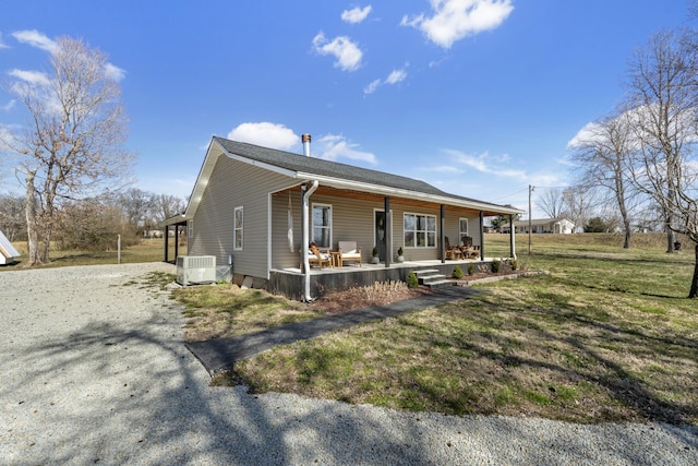 view of front facade featuring covered porch, driveway, a front lawn, and central AC unit