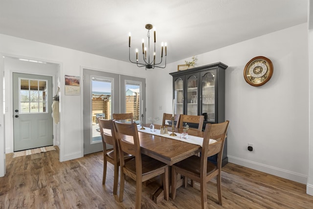 dining room featuring a chandelier, french doors, wood finished floors, and baseboards