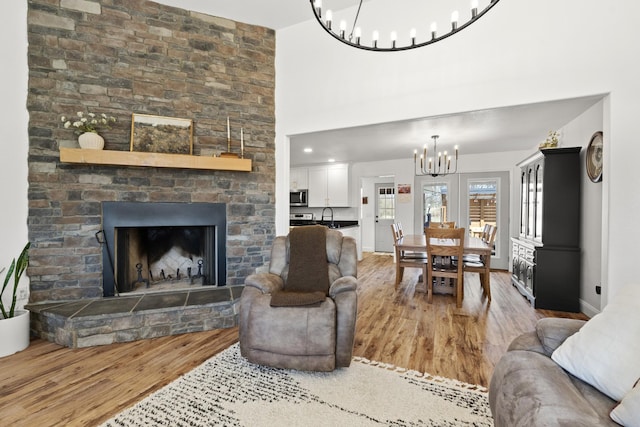 living area featuring baseboards, a fireplace, wood finished floors, and an inviting chandelier