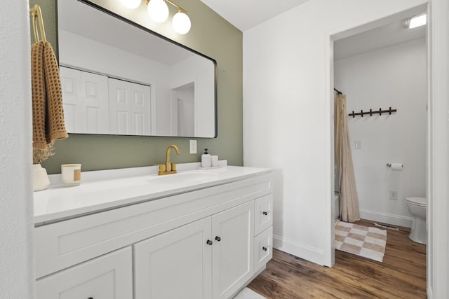 full bathroom featuring toilet, baseboards, wood finished floors, and vanity