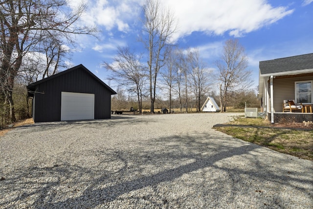 view of yard featuring a garage, gravel driveway, cooling unit, and an outbuilding