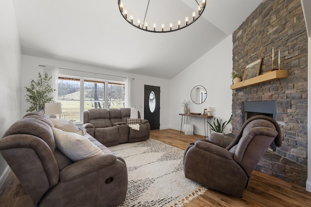 living room featuring high vaulted ceiling, baseboards, wood finished floors, and a stone fireplace