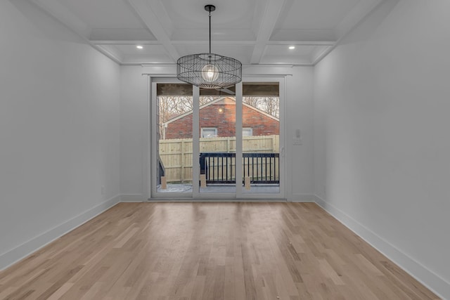 unfurnished dining area with light wood-style flooring, baseboards, and beamed ceiling