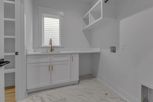 laundry area featuring washer hookup, a sink, baseboards, marble finish floor, and cabinet space