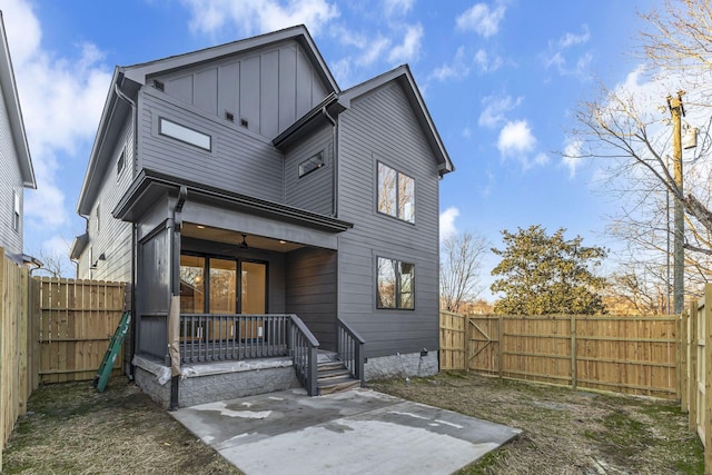 rear view of house featuring a patio, board and batten siding, and a fenced backyard