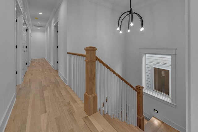 hall featuring light wood-type flooring, recessed lighting, baseboards, and an upstairs landing