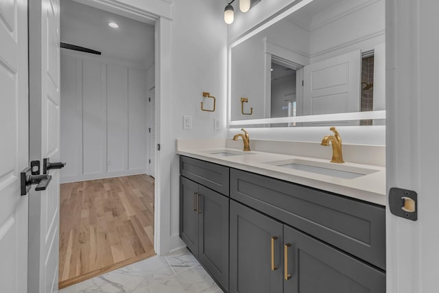 full bath with marble finish floor, a sink, a decorative wall, and double vanity