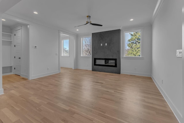 unfurnished living room with ceiling fan, light wood-style flooring, recessed lighting, a large fireplace, and crown molding