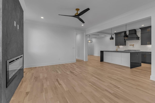 unfurnished living room with baseboards, light wood finished floors, a ceiling fan, and crown molding