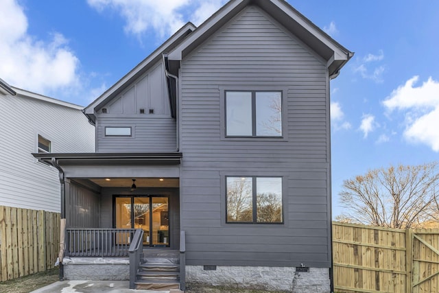 rear view of property featuring crawl space, covered porch, fence, and board and batten siding