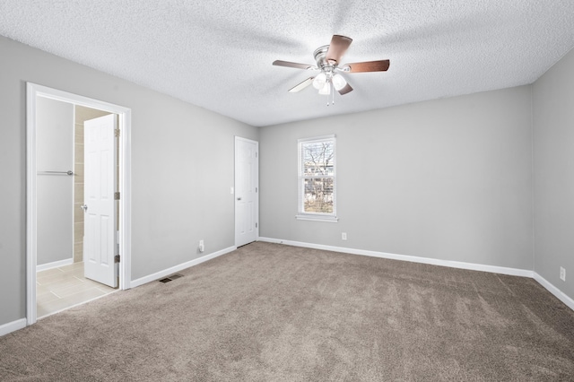 carpeted empty room with baseboards, a textured ceiling, visible vents, and a ceiling fan