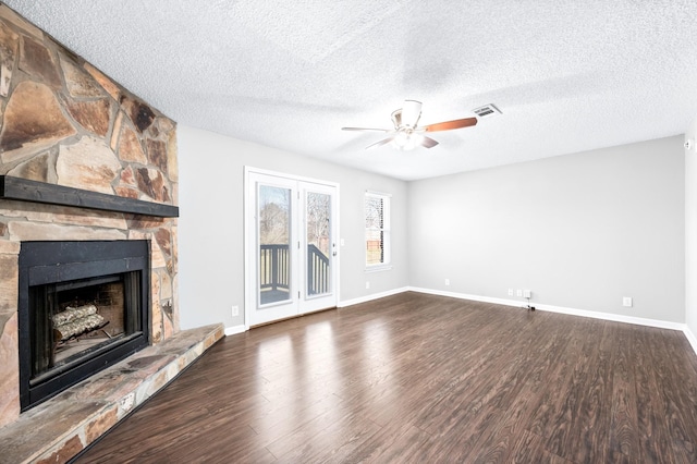 unfurnished living room with a fireplace, wood finished floors, visible vents, and a ceiling fan