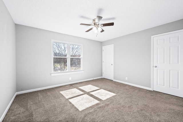 unfurnished bedroom with carpet flooring, a textured ceiling, and baseboards