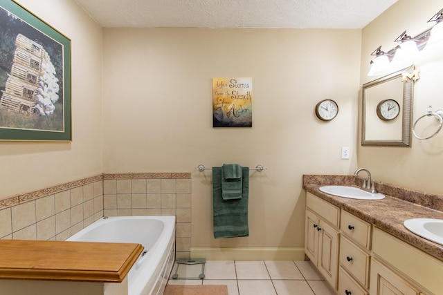 bathroom with double vanity, a bath, tile patterned flooring, a textured ceiling, and a sink