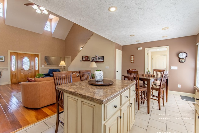 kitchen featuring a center island, a breakfast bar area, light tile patterned floors, cream cabinets, and a textured ceiling