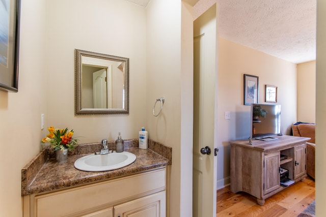 bathroom with a textured ceiling, vanity, and wood finished floors