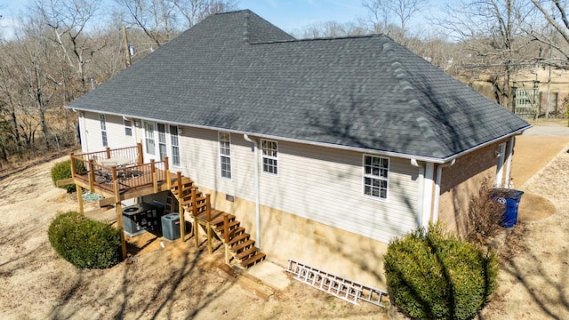 rear view of property featuring a deck, central AC, a shingled roof, and stairway