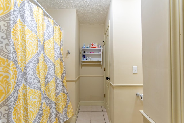 bathroom with a textured ceiling, baseboards, and tile patterned floors