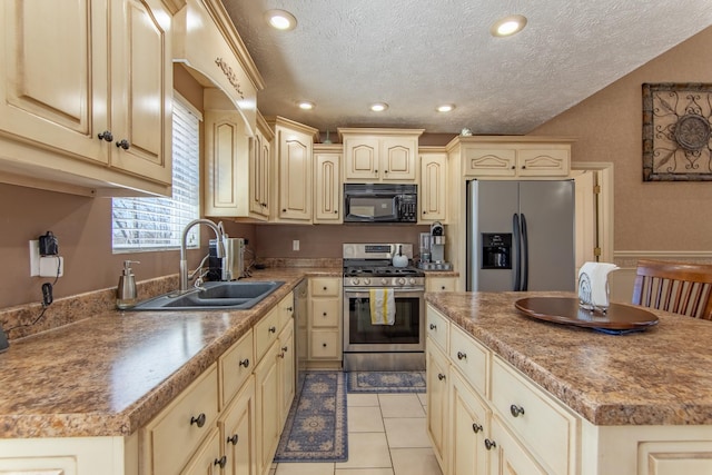 kitchen with light tile patterned floors, stainless steel appliances, a kitchen island, a sink, and a textured ceiling